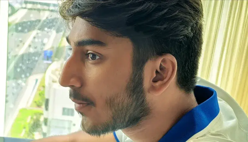 Close-up portrait of Nikesh looking out beside a window.